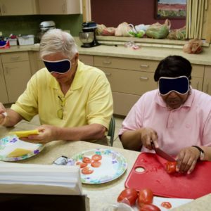 Seniors in the Kitchen - Ralph fixes a plate of sliced cheese while Sheila slices tomatoes for a sanwitch bar