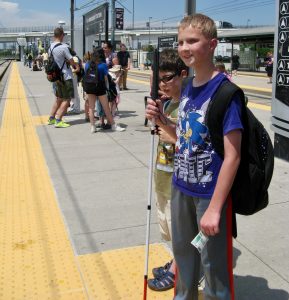 Ty and Seamus standing with their canes waiting on the train