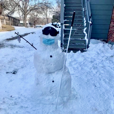 A snow person wearing sleepshades and pandemic mask