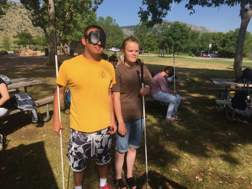 Two smiling blind teenagers at Big Soda Lake near the mountains