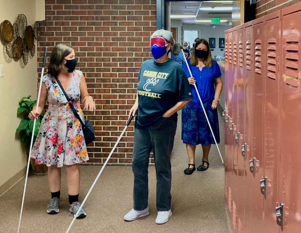 a senior woman navigates the hallway among other students with her instructor following