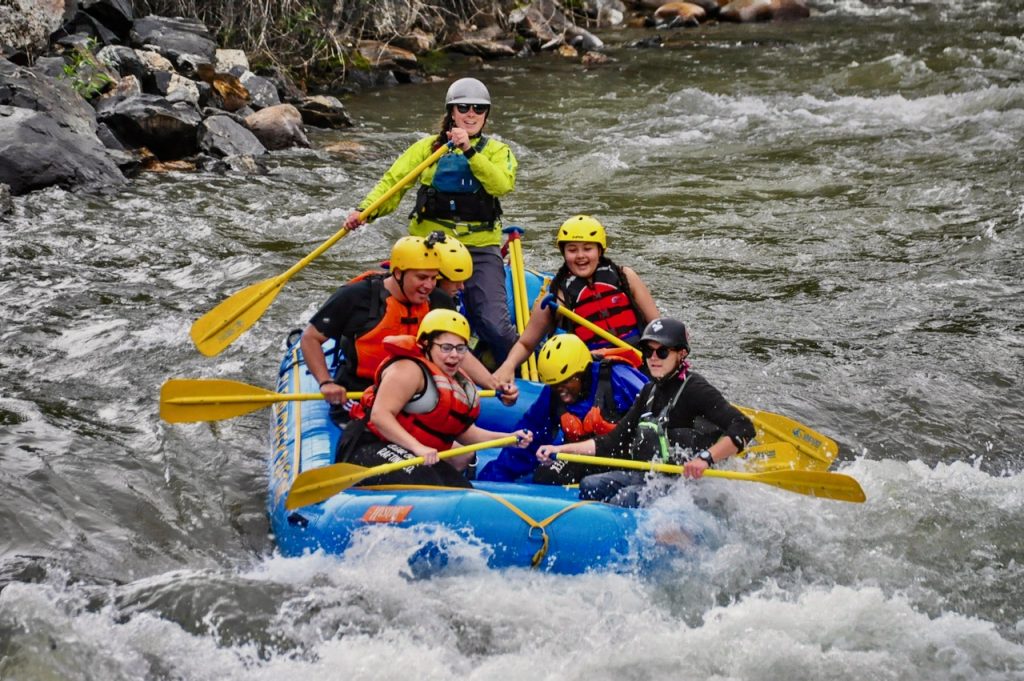 A raft of summer youth lets out a yell as they dive into a churning hole of white water on Clear Creek.