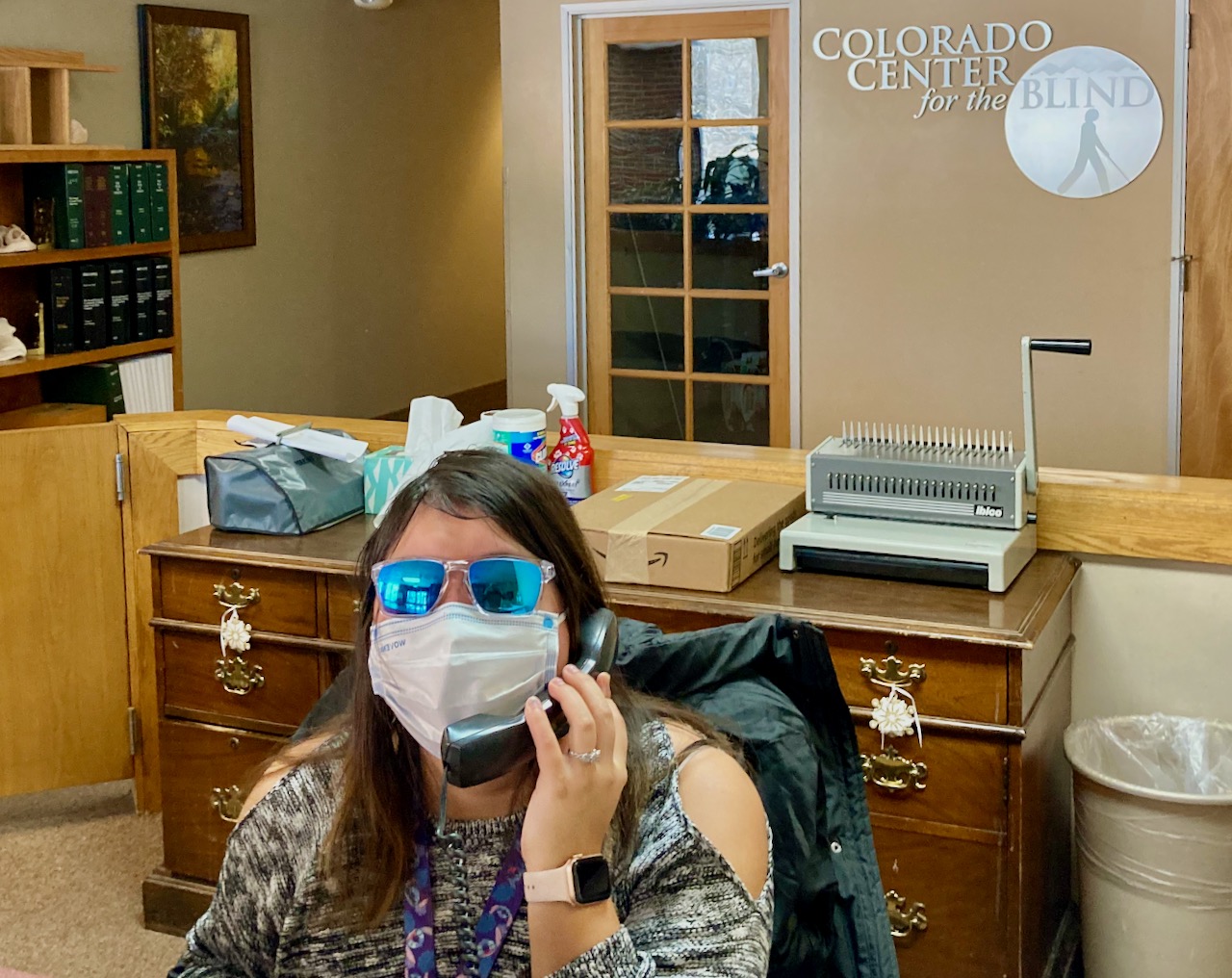 Beth with cool Blue Mirrored Glasses answering the phone at the front desk