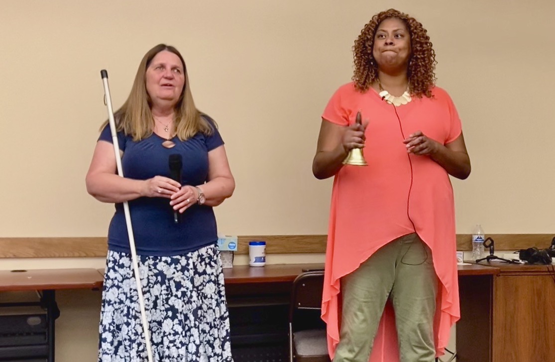 Jamila rings her Bell of Freedom - Julie stands to her left with the microphone