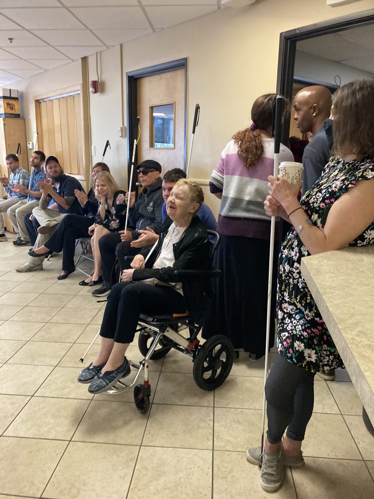 People clap and cheer as Diane McGeorge comes in to the Meeting Room on her 90th Birthday