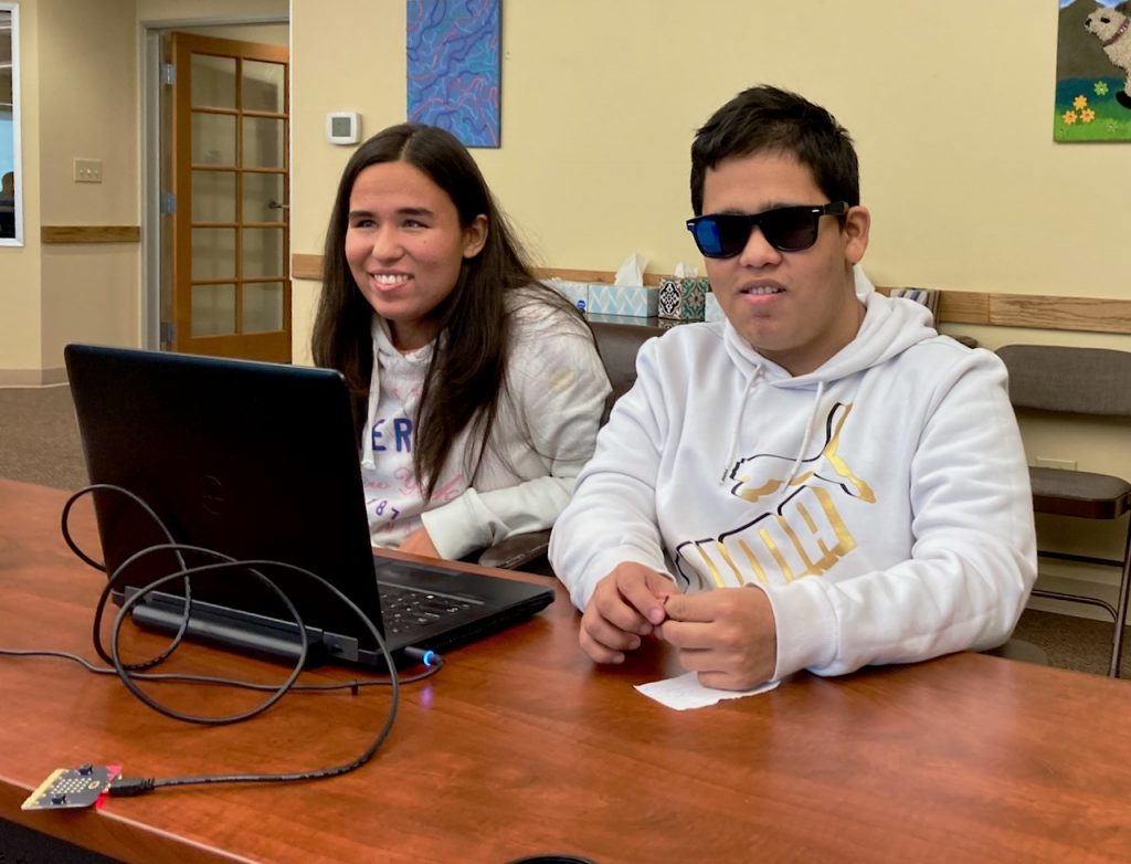 a young woman and a young man with laptop and USB cable and card on a table