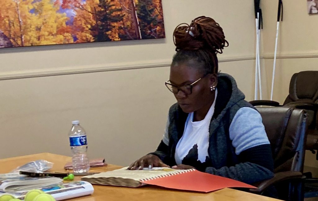 a woman with a braille book and an alphabet card