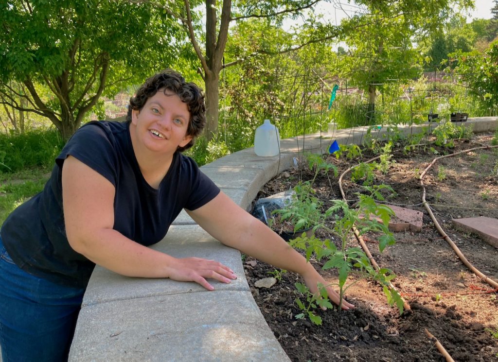 Sarah reaches into the raised bed as she finishes putting in a tomato plant