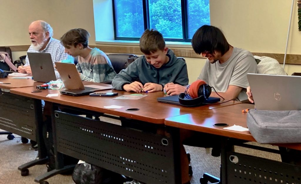 Pairs of youth share laptops at a long table