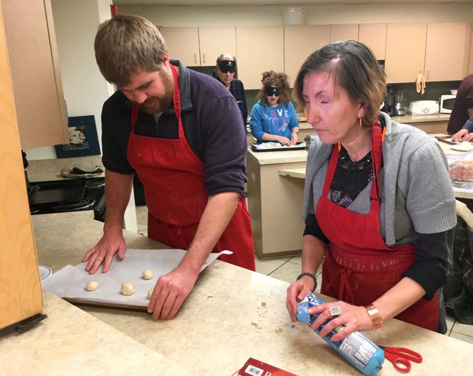 Two people roll cookie dough into balls