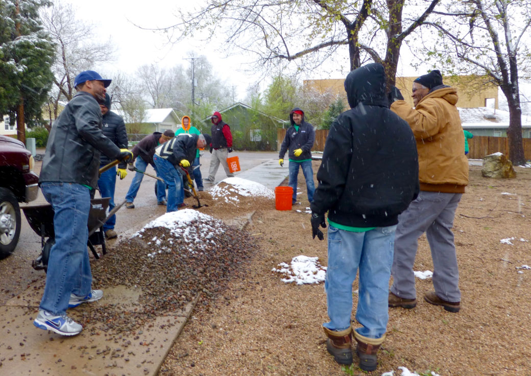 Workers with shoels, rakes and brooms in the snow and rain