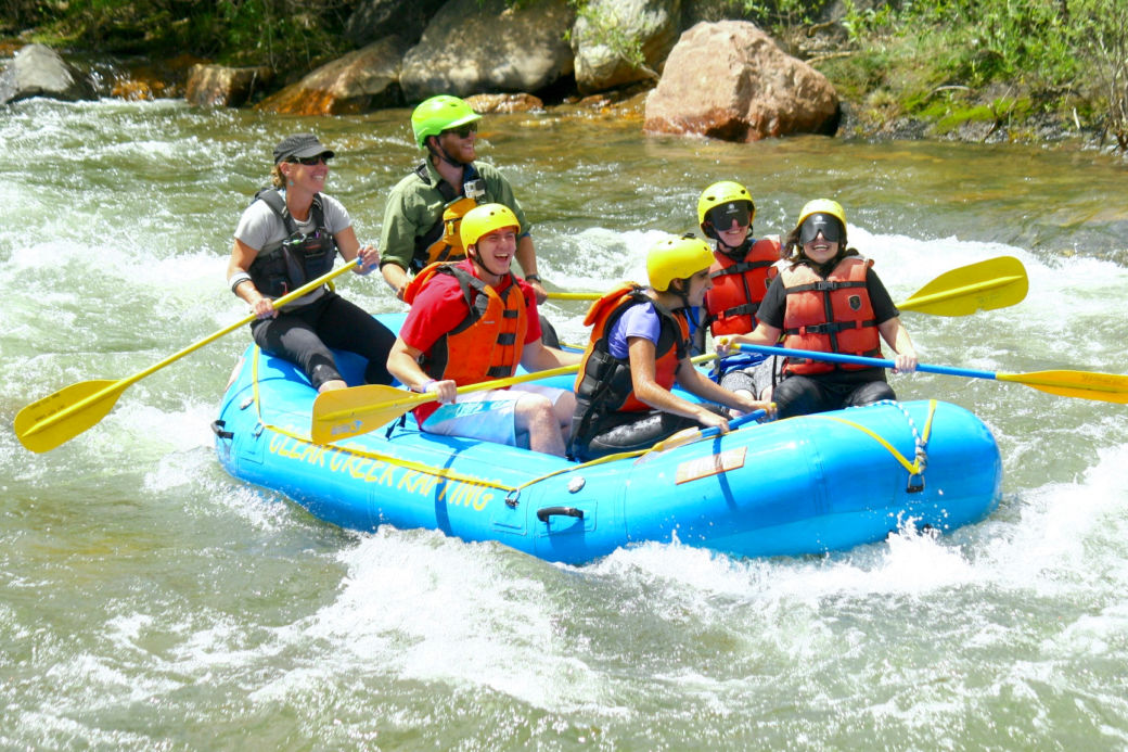 Summer youth grin ear to ear as they paddle hard through rushing white water
