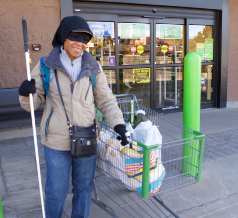 a smiling woman with a cart full of groceries outside the store