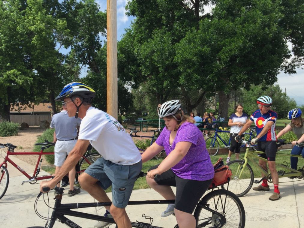 Summer students Mary and Cheyenne each mount a tandem bike with EyeCycle Volunteers while Christina waits her turn