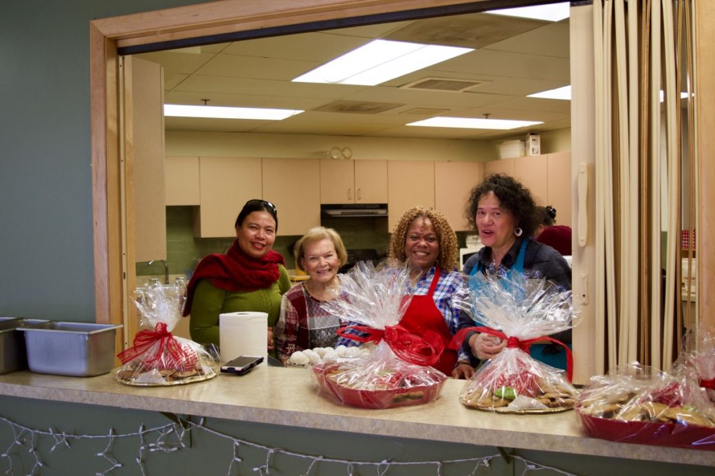 Mary Ann, Priscilla and Blanca in the Serving window with lots of finished trays of cookies wrapped up and tied with ribbons