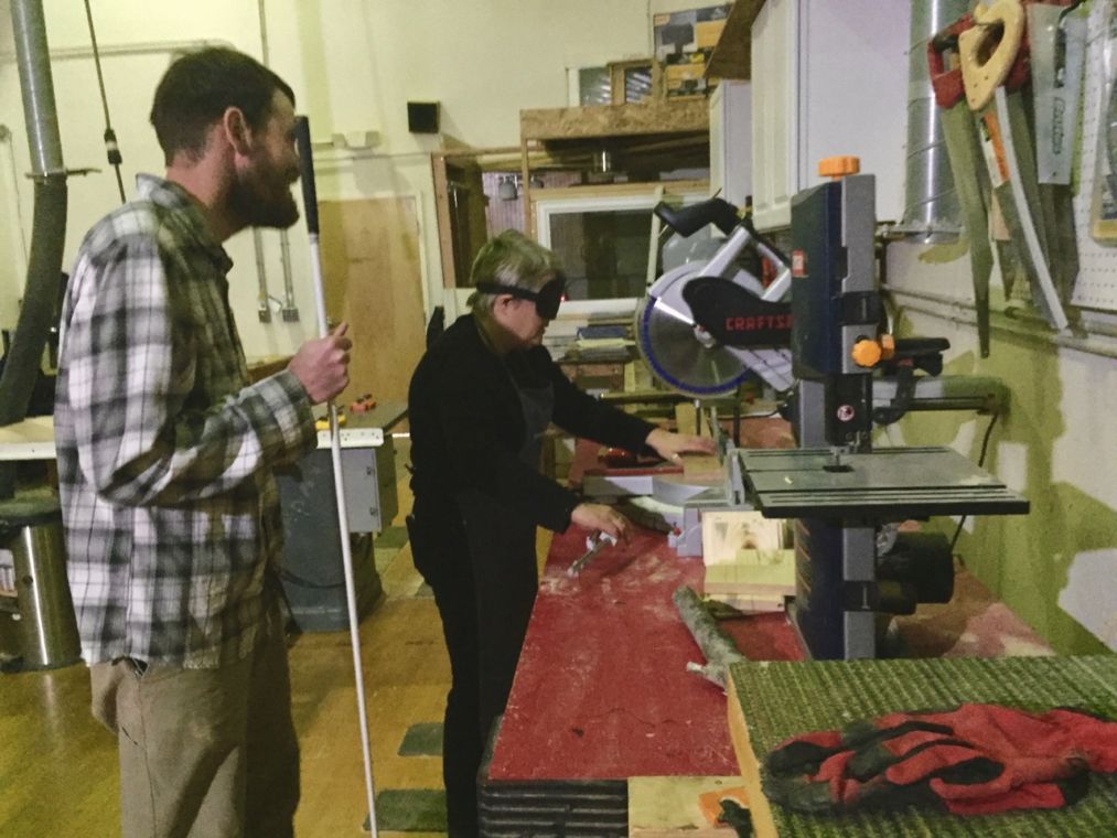 David asks Cathy if we want to make a perfectly square board how are we going to do that. Cathy holds a click rule and lines a board up on the gliding chop saw.