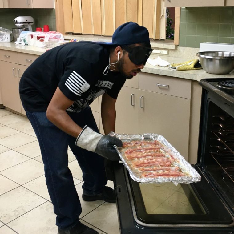 Christian pulls a sizzling tray of bacon out of a hot oven as part of the Christmas breakfast burrito project