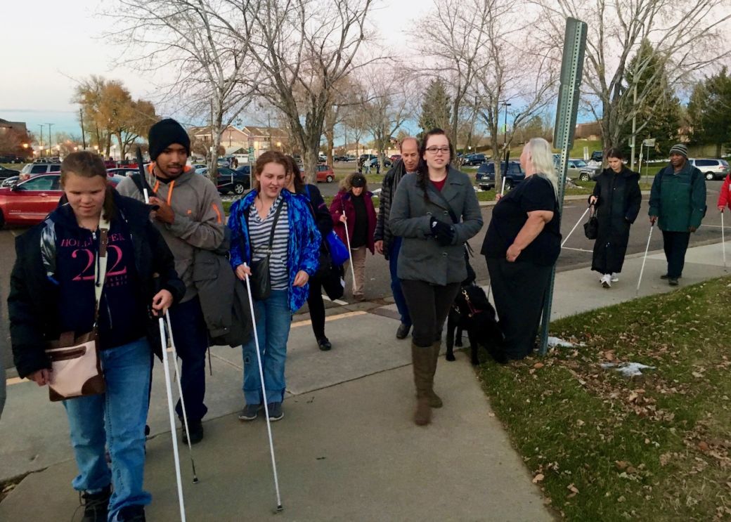 Large group of CCB staff and students walk along the curve of the sidewalk toward the Art Gallery building