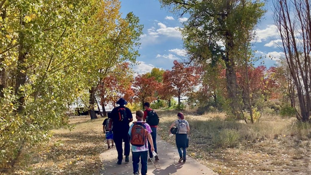CCB folks Lewie, Abdi, Matthew Cameron and Skysha walk along a colorful tree lined path leading toward Bowles Ave.